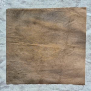 Tela artesanal de algodón teñida con tintes ecológicos en tonos marrón, marrón dorado y óxido intenso.