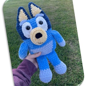 May include: A blue and yellow crocheted stuffed toy resembling a dog. The toy has large, round eyes and a friendly expression.