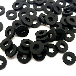 May include: A pile of black rubber washers with a star-shaped cutout in the centre.