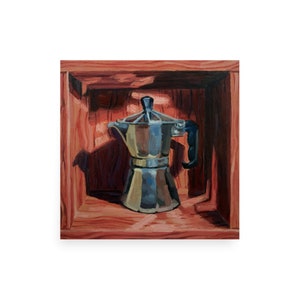 May include: A silver coffee pot with a black handle sits inside a wooden box with a red-brown stain. The box is open and the coffee pot is in the center of the box.