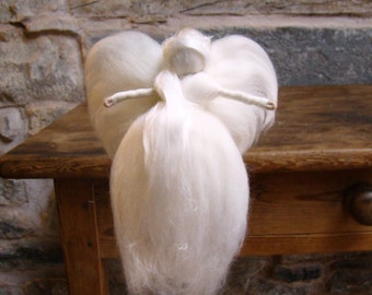 May include: A handmade white angel figurine with outstretched arms. The angel has large, fluffy wings and a flowing gown. The figure is made of soft, white material, possibly wool or felt, and sits on a wooden surface.