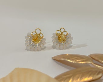 Puede incluir: Un par de delicados pendientes de oro con un racimo de cuentas blancas en forma de flor.