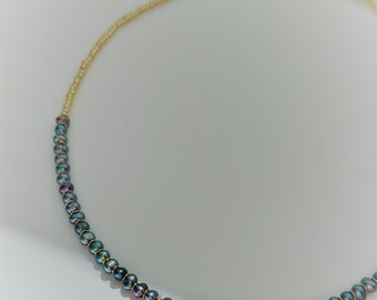 Puede incluir: Un collar de cadena dorada con un pequeño dije dorado y una hebra de perlas azul oscuro.