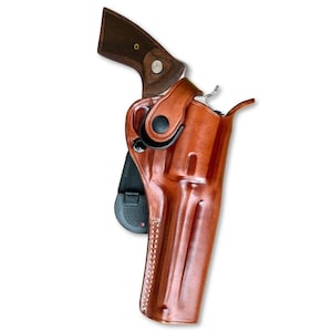 May include: A brown leather holster with a stitched seam and a black snap closure. The holster is designed to hold a revolver.
