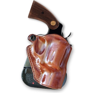 May include: A brown leather holster with a stitched edge, designed to hold a revolver. The holster is shown with a gun inside, but the gun is not visible.