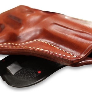 May include: A brown leather holster with white stitching. The holster is folded in half, showing the inside of the holster.