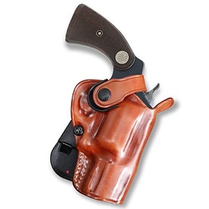 May include: A brown leather holster with a black clip and a black gun inside. The holster has a strap that goes around the gun.