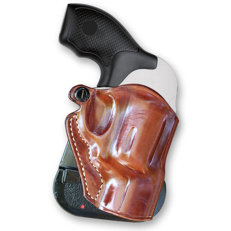 May include: A brown leather holster with a stitched design, holding a black handgun with a textured grip.