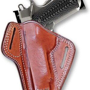 May include: A brown leather holster with white stitching for a handgun. The holster has a belt loop and a  "MASC HAND MADE" logo.