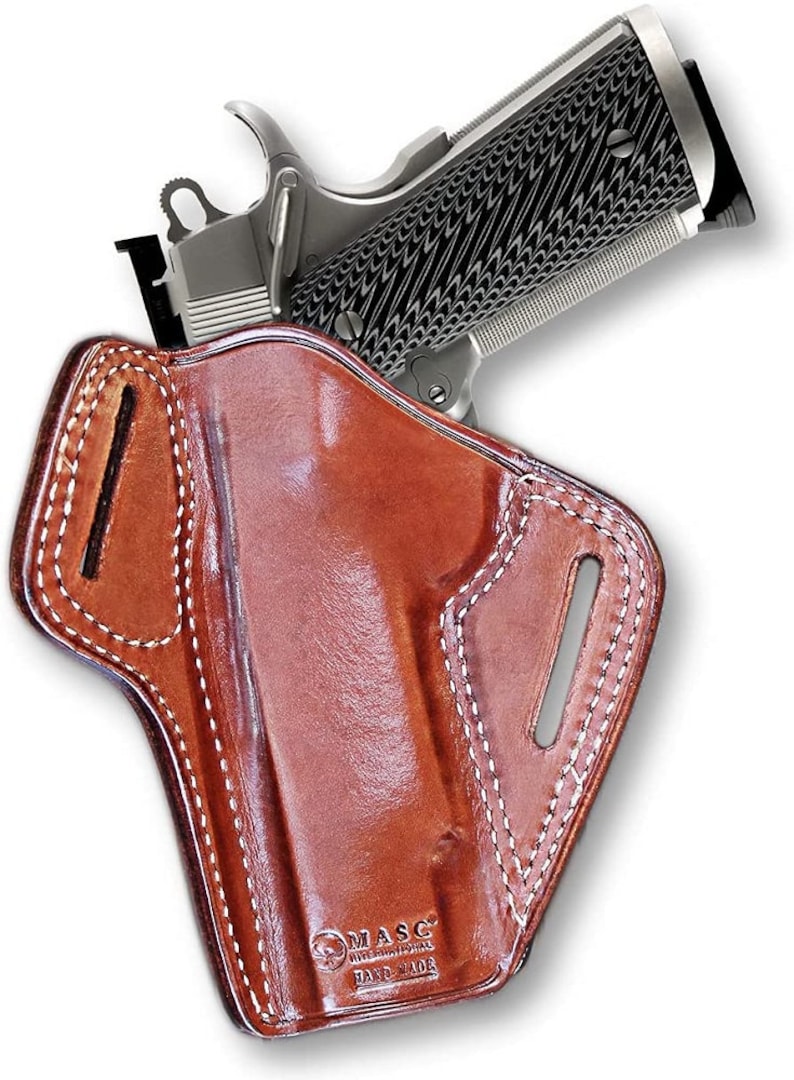 May include: A brown leather holster with white stitching for a handgun. The holster has a belt loop and a  "MASC HAND MADE" logo.