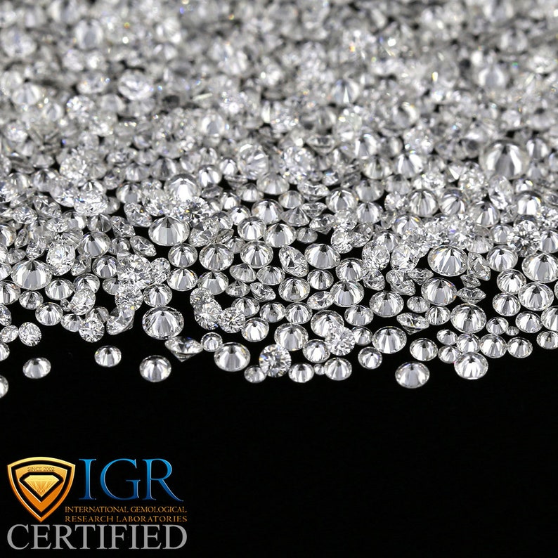 May include: A close-up shot of a collection of sparkling, round-cut diamonds. The diamonds are scattered across a black surface, creating a dazzling display of light and brilliance. The image includes the text "IGR CERTIFIED".