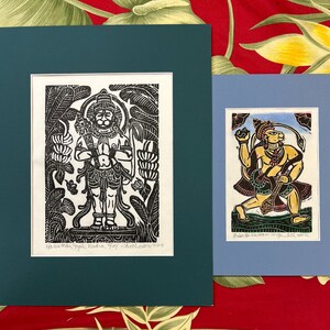 May include: Two framed black and white woodblock prints of Hindu deities. The print on the left depicts a standing figure with a crown and a third eye. The print on the right depicts a figure with a crown and a third eye holding a staff. The print on the left is titled "Hanumanthapali Buddha" and the print on the right is titled "Baba with Hanuman wife Sita & some"
