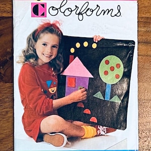 Puede incluir: Una caja de juego Colorforms vintage con una niña sosteniendo una pizarra de fieltro negro con formas geométricas coloridas. La caja tiene un diseño rosa y blanco con la palabra "Colorforms" y el logotipo de Butterick.