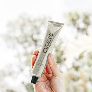 May include: A silver tube of Oasis Daily Sunscreen SPF 50 mineral body sunscreen for all skin types. The tube is 1.7 fl oz (50 ml).