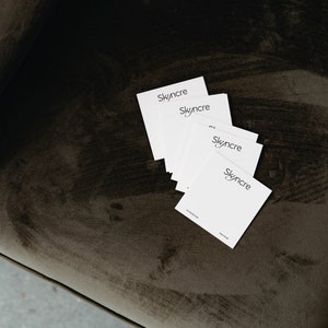 Può includere: Un mazzo di biglietti da visita bianchi con il testo "Skyencre" stampato in nero su ogni biglietto. I biglietti sono su una superficie di velluto marrone.