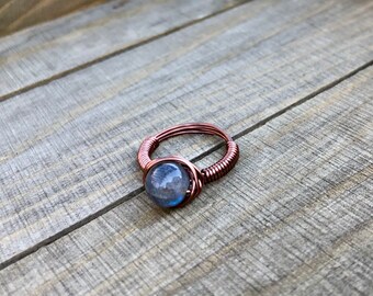 May include: A copper wire wrapped ring with a blue labradorite gemstone.