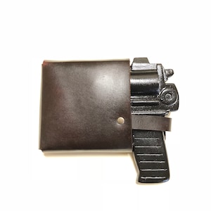 May include: A black metal toy gun with a brown leather holster. The gun has a barrel, a handle, and a trigger. The holster has a flap that closes over the gun.