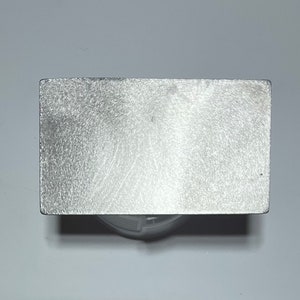 May include: A silver metal square plate with a brushed finish.