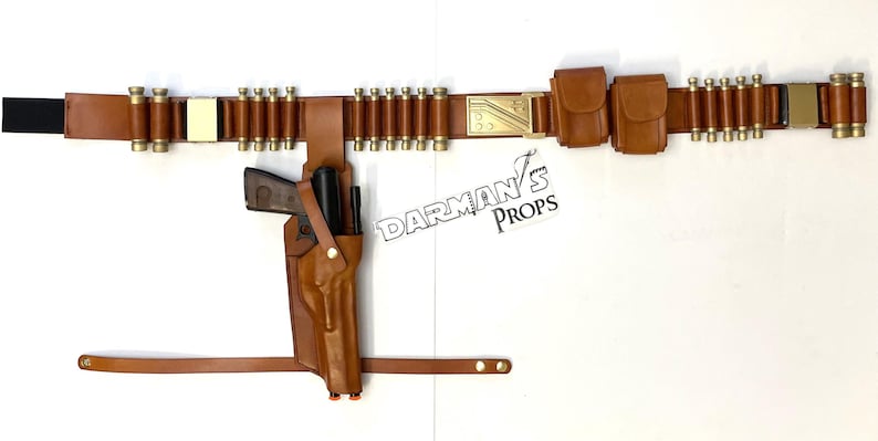 May include: A brown leather belt with a gold buckle and multiple pouches. The belt has a row of brass bullet casings attached to it. A brown leather holster with a gun is attached to the belt.