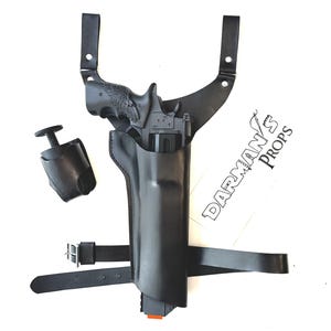 May include: Black leather shoulder holster with a matching magazine pouch. The holster is designed to hold a handgun and features adjustable straps and a belt loop. The image also includes a handgun.