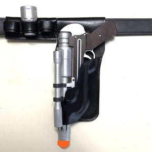 May include: A black leather belt with a silver flashlight holder and a black holster for a silver and black pistol.