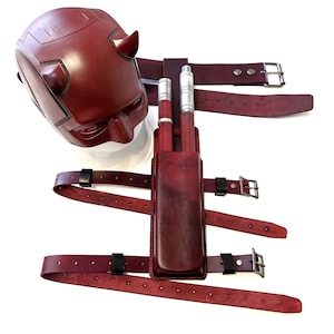 May include: A red leather costume mask with horns and a matching leather belt with a holster for two silver batons.