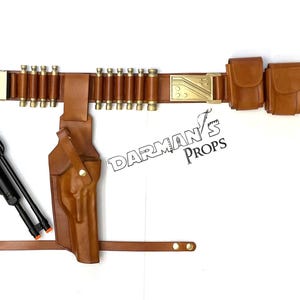 May include: A brown leather belt with a gold buckle and multiple pouches. The belt has a series of loops for holding ammunition. A black pistol with a brown leather holster is attached to the belt. The text "Darman's Props" is visible on the image.
