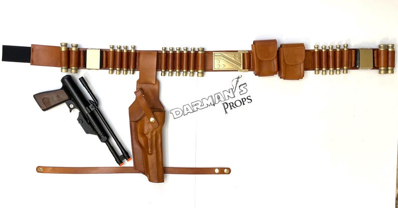 May include: A brown leather belt with a gold buckle and multiple pouches. The belt has a series of loops for holding ammunition. A black pistol with a brown leather holster is attached to the belt. The text "Darman's Props" is visible on the image.