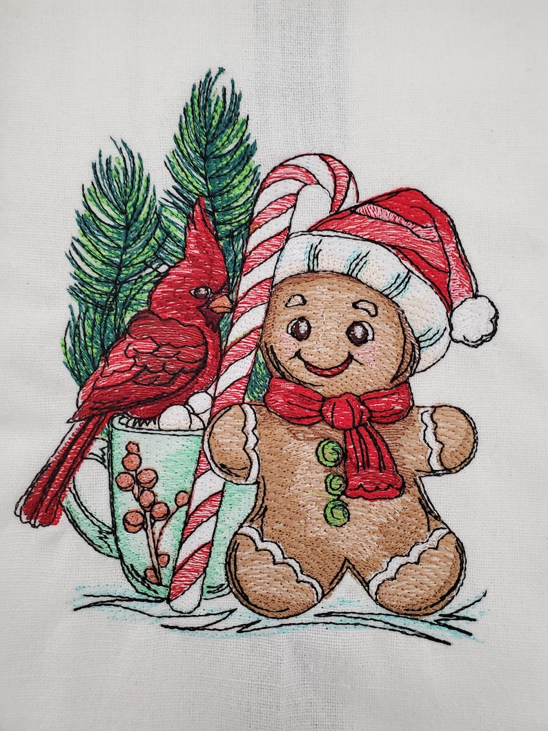 May include: Embroidered Christmas design featuring a red cardinal bird, a gingerbread man wearing a Santa hat and scarf, a candy cane, and a mug of hot cocoa with marshmallows. The design is set against a backdrop of evergreen branches.