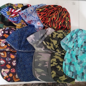 May include: A collection of colorful welding caps in various patterns. Designs include camouflage, flames, stars, and patriotic themes. The caps are made of fabric and feature a sewn construction.
