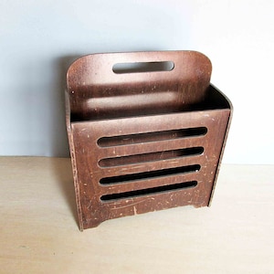 May include: A brown wooden magazine rack with a handle on the top and five open shelves.