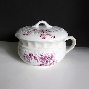 May include: White ceramic chamber pot with a lid. The pot has a floral design in shades of purple.