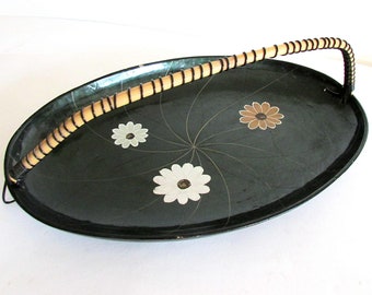 May include: A black oval serving tray with a bamboo handle. The tray has a white and brown floral design.