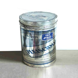 May include: A vintage metal can of Heischman Frozen Egg White. The can is silver with blue lettering and a blue label that reads "Egg White". The can also has the text "30 LBS. NET".