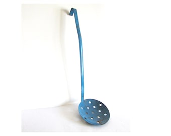 Puede incluir: Un espumadera de metal azul vintage con un mango largo y un cuenco perforado. La espumadera está diseñada con un gancho en el extremo del mango para colgarla. Este utensilio de cocina se utiliza probablemente para retirar alimentos de líquidos calientes.