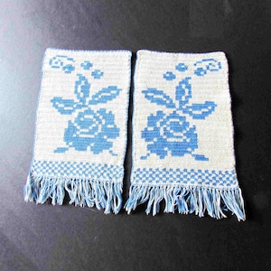 May include: Two white crocheted pot holders with blue floral designs and fringe trim.