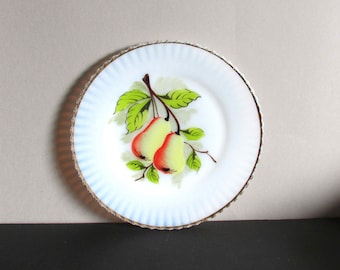 May include: A white ceramic plate with a blue and white scalloped edge. The plate features a hand-painted design of two pears on a branch with green leaves.