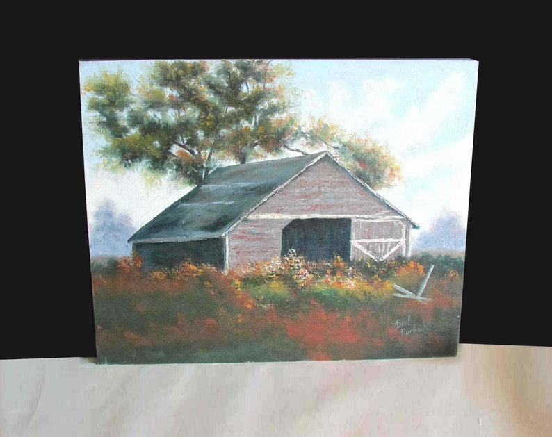 May include: A painting of a rustic wooden barn with a gray roof, set against a backdrop of a green field and a blue sky. The barn has a large open door and is surrounded by a field of wildflowers. The painting is signed "Earl Murphey" in the lower right corner.