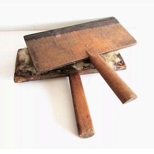 May include: Antique wooden wool carding tool with two wooden boards and a handle. The boards are covered in a layer of wool fibers.