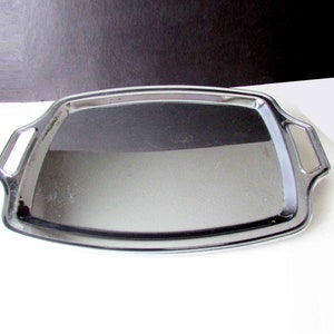 May include: A silver serving tray with two handles. The tray is rectangular with rounded corners and a slightly raised edge.