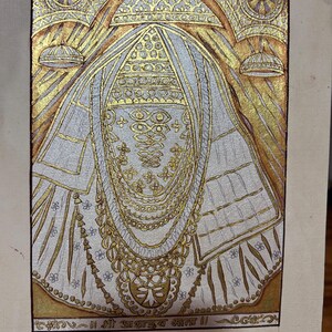 May include: An ornate painting featuring a central figure adorned with gold jewelry and a detailed headdress. The artwork uses gold and silver metallic paint on a light background, with text at the bottom. The style is reminiscent of traditional religious art.