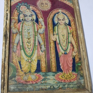 Könnte beinhalten: Gerahmter Vintage-Druck, der zwei Figuren in traditioneller Kleidung vor dem Hintergrund von Bögen und einer Sonne zeigt. Die Figuren sind mit Schmuck geschmückt und stehen auf Lotusblumen. Der Rahmen ist goldfarben.