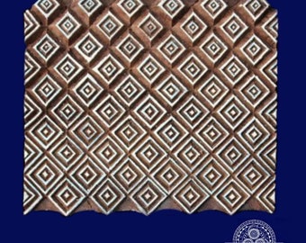 Puede incluir: Un bloque de impresión de madera con un patrón geométrico de cuadrados blancos sobre un fondo marrón. El bloque está tallado con un patrón repetitivo de cuadrados y diamantes.