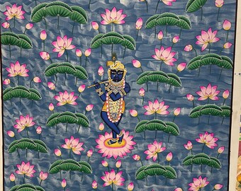 May include: An Indian painting depicts a blue-skinned figure playing a flute, standing on a pink lotus flower. The background is a blue water scene with numerous pink lotus flowers and green lily pads. The artwork is framed with a white border.