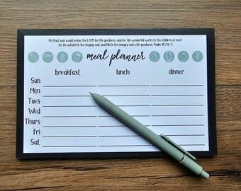 May include: A black and white meal planner with a green border. The planner has a quote from Psalm 107:8-9, "Oh that man would praise the LORD for His goodness, and for His wonderful works to the children of men! for He satisfieth the longing soul, and filleth the hungry soul with goodness." The planner has sections for breakfast, lunch, and dinner, and includes a list of days of the week: Sunday, Monday, Tuesday, Wednesday, Thursday, Friday, and Saturday.