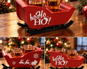 Puede incluir: Una bandeja de servicio roja con forma de trineo y patines negros, con el texto blanco "ho Ho HO!" y un icono de gorro de Papá Noel. La bandeja contiene cuatro vasos de chupito transparentes llenos de un líquido ámbar y gráficos de renos.