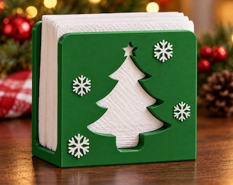 Puede incluir: Un servilletero de madera verde con un recorte en forma de árbol de Navidad en el centro y cuatro adornos de copos de nieve blancos fijados en el panel frontal, lleno de una pila de servilletas de papel blancas plegadas.