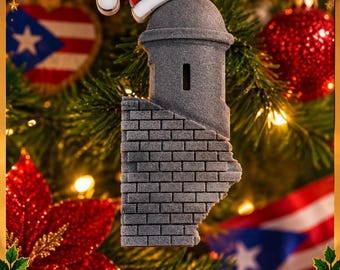 Puede incluir: Un adorno gris y texturizado con forma de garita, que presenta una base con patrón de ladrillos y una parte superior redondeada. El adorno está rematado con un gorro de Papá Noel rojo y blanco y cuelga de un lazo de cuerda marrón.
