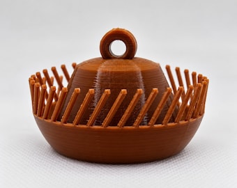 Puede incluir: Un objeto marrón impreso en 3D con una base redondeada y lisa, una cúpula central y un pequeño lazo circular en la parte superior. El perímetro está rodeado por una serie de finas láminas verticales diagonales espaciadas uniformemente.