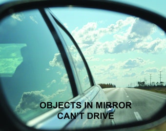 Puede incluir: Espejo retrovisor lateral de un coche que refleja un cielo azul brillante con nubes blancas y una carretera larga y recta. El texto "OBJECTS IN MIRROR CAN'T DRIVE" se muestra en la parte inferior del espejo.